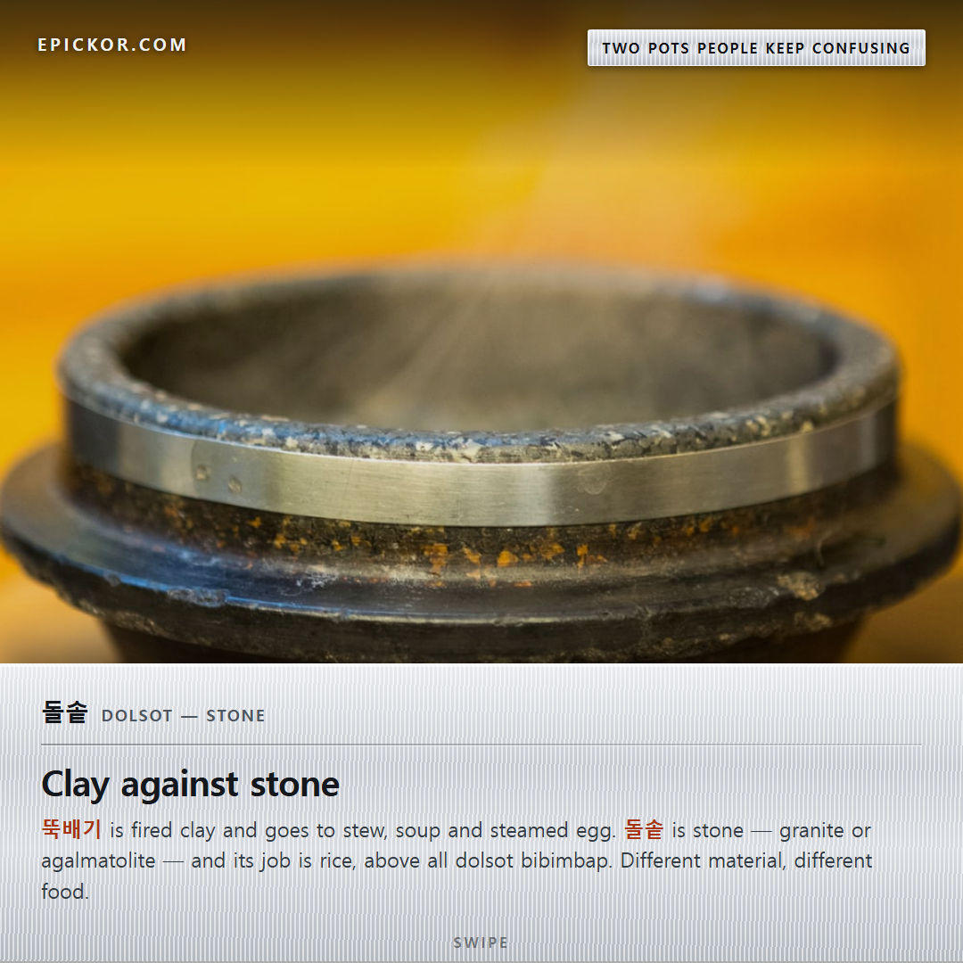 An empty grey-black stone dolsot with a steel band around the rim, steaming on a wooden trivet
