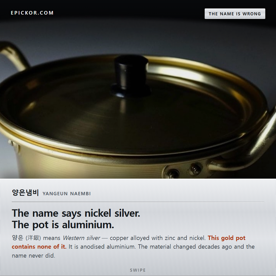 A gold anodised aluminium 양은냄비 (yangeun naembi) with two side handles and a black lid knob, lit against a dark background — the yellow pot Koreans actually picture
