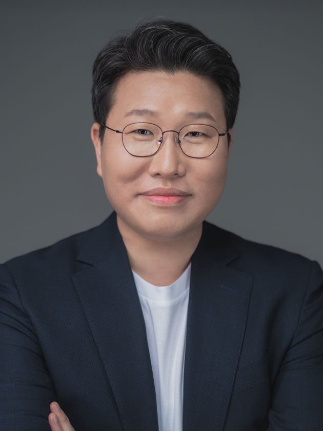Coreline Soft CEO Kim Jin-kook, wearing glasses and a navy jacket, arms folded, against a grey background.