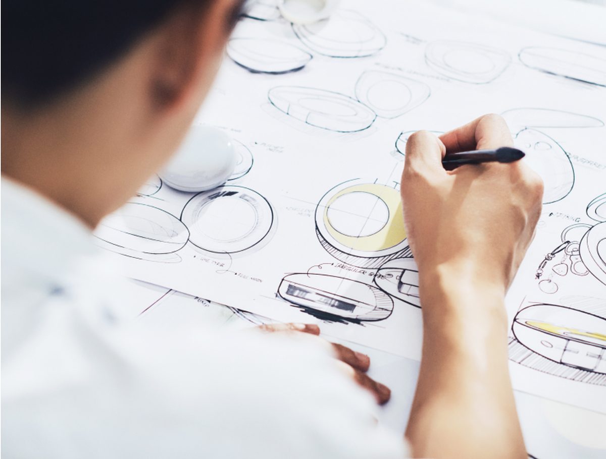 An official COSMAX image shows a designer sketching circular cosmetic packages during product development.