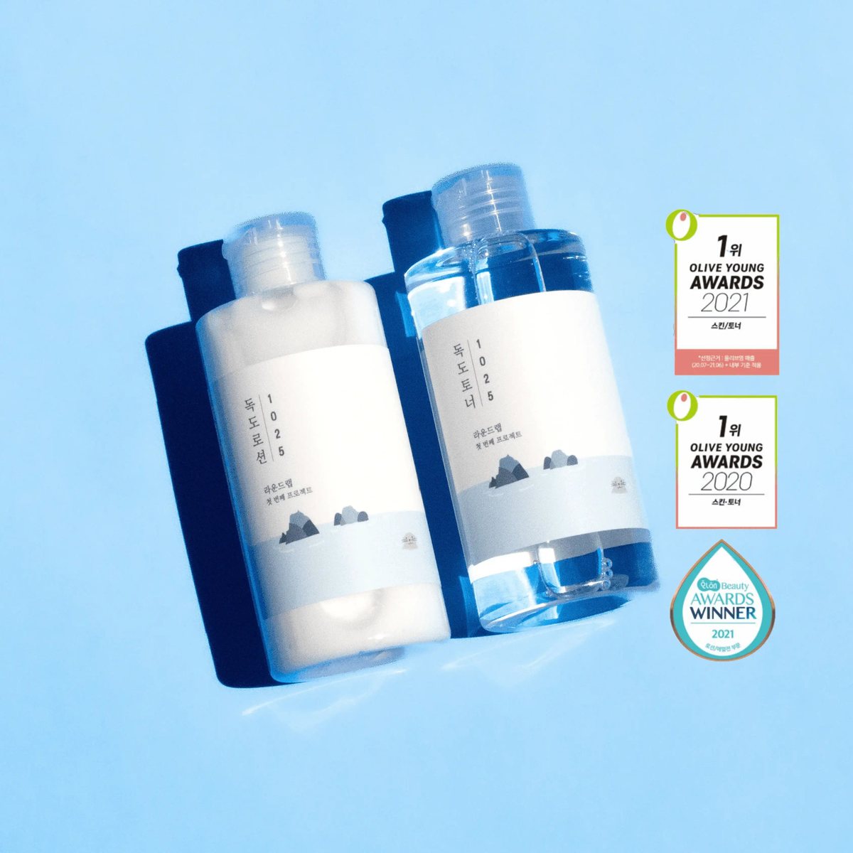 Round Lab 1025 Dokdo Lotion and 1025 Dokdo Toner bottles side by side on a blue background, with Olive Young Awards 2020 and 2021 badges.