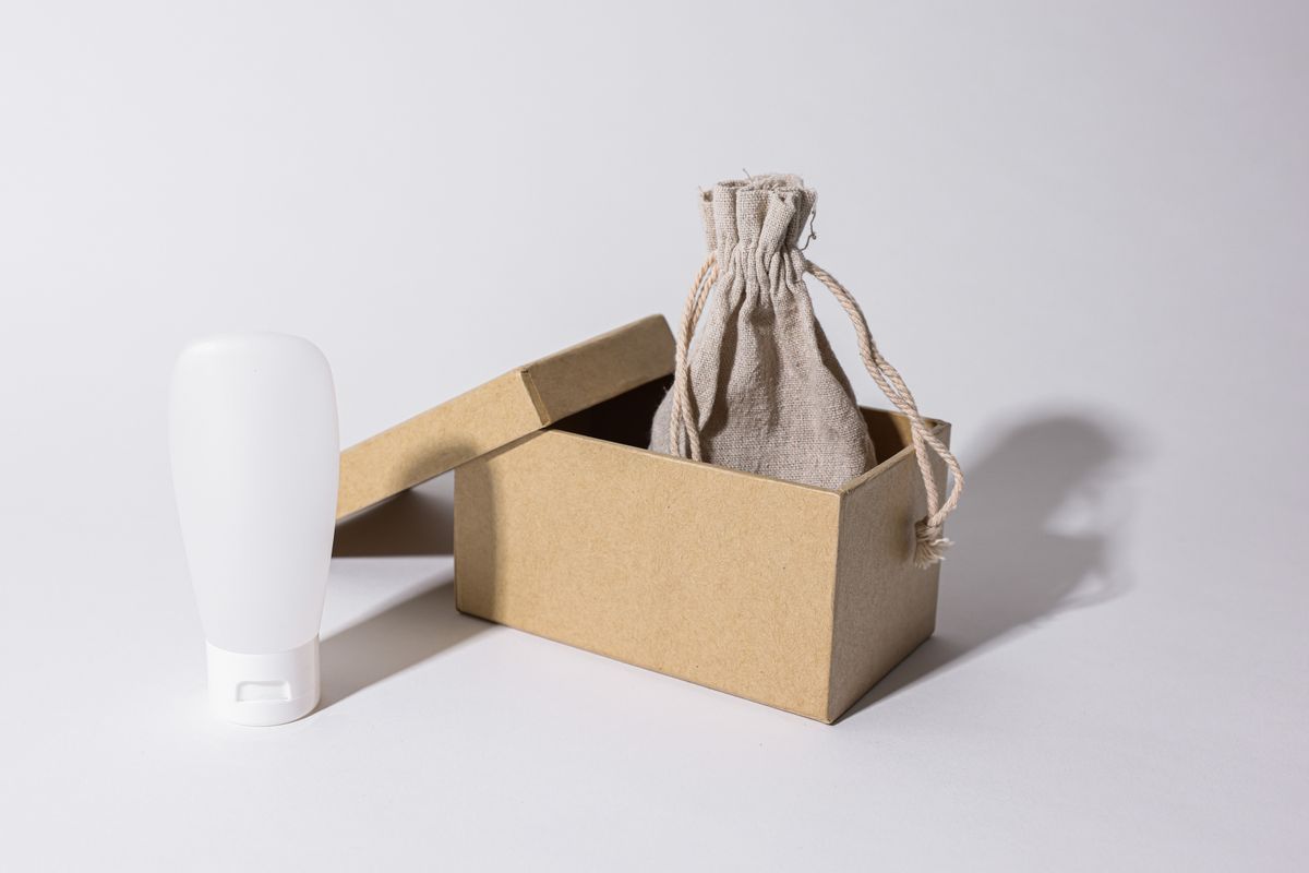 A cosmetic bottle, carton, and fabric pouch show why packaging buyers should define each component before contacting suppliers.