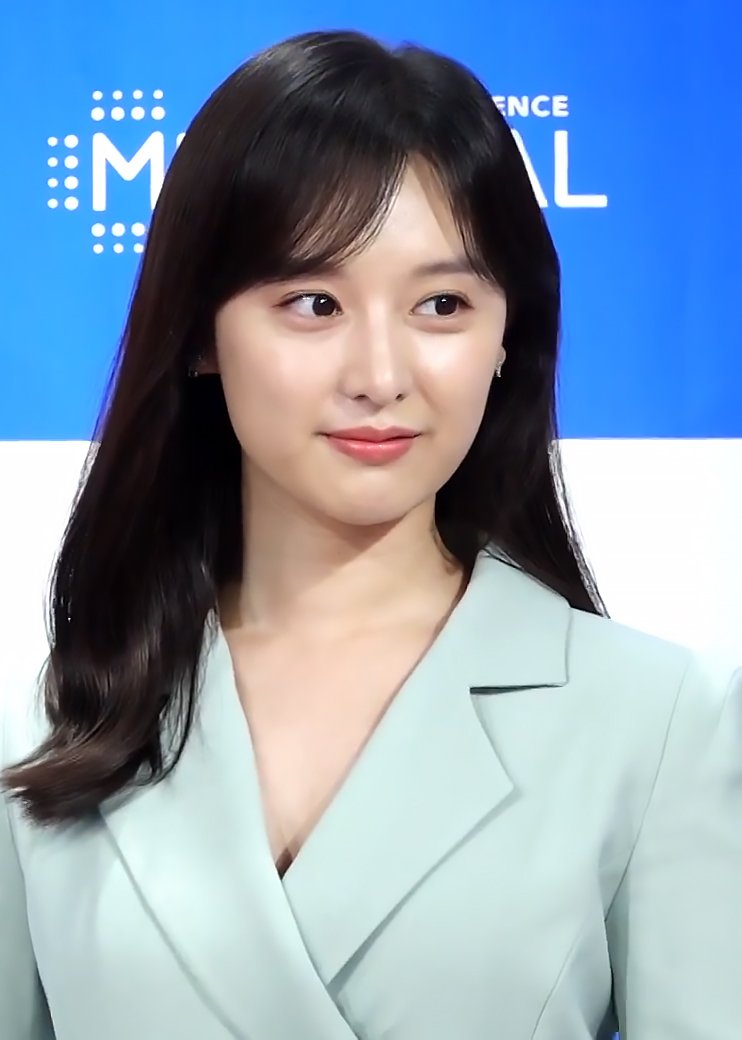 Actress Kim Ji-won, in a pale green jacket, smiling in front of a blue MEDIHEAL backdrop at a product launch.
