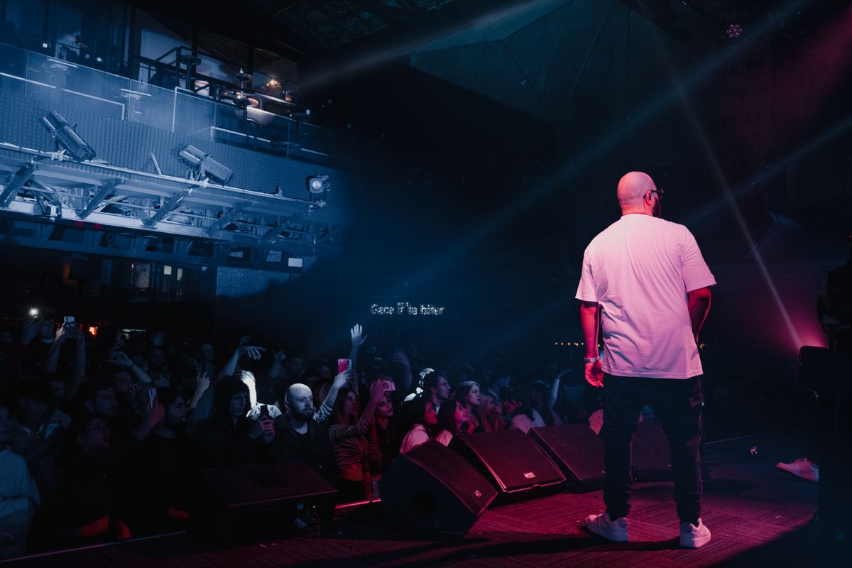 A rapper performing live on stage with audience energy and concert lighting.