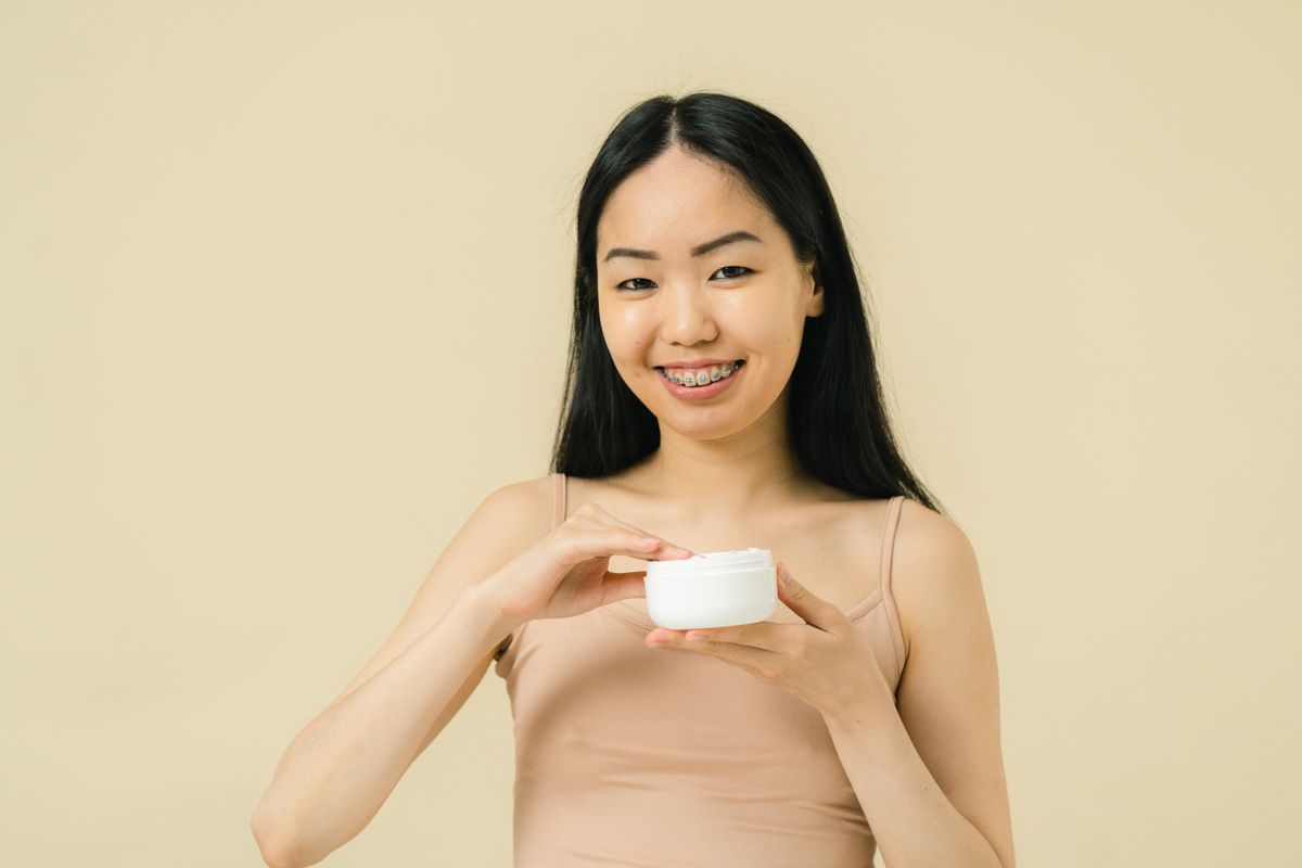 A person holding a simple skincare cream jar