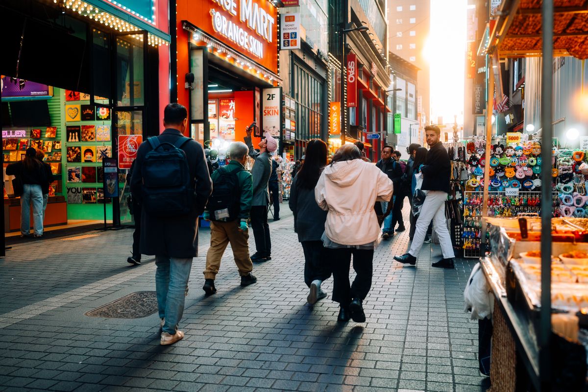 A busy Seoul market street with colorful stalls and shoppers.