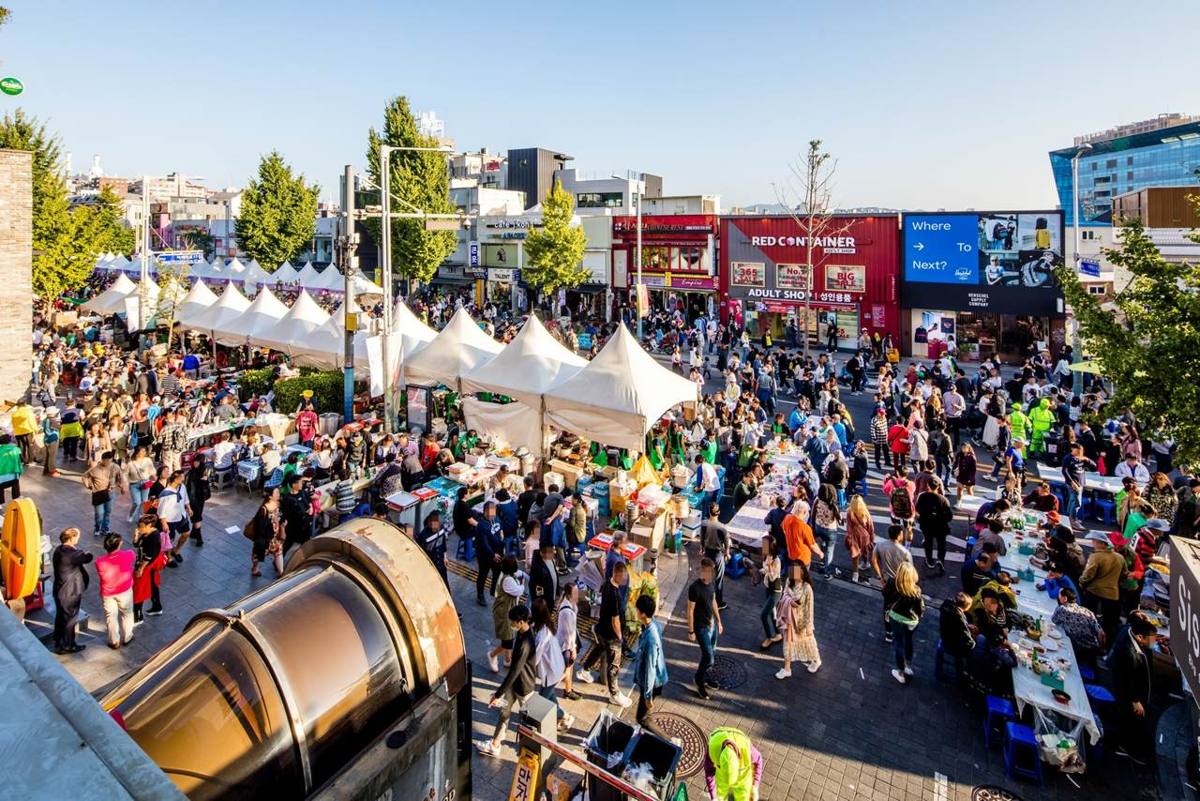 Itaewon-ro in Yongsan, Seoul, during the Itaewon Global Village Festival in October 2019, with white tents, food tables and crowds in front of shops and a large screen.