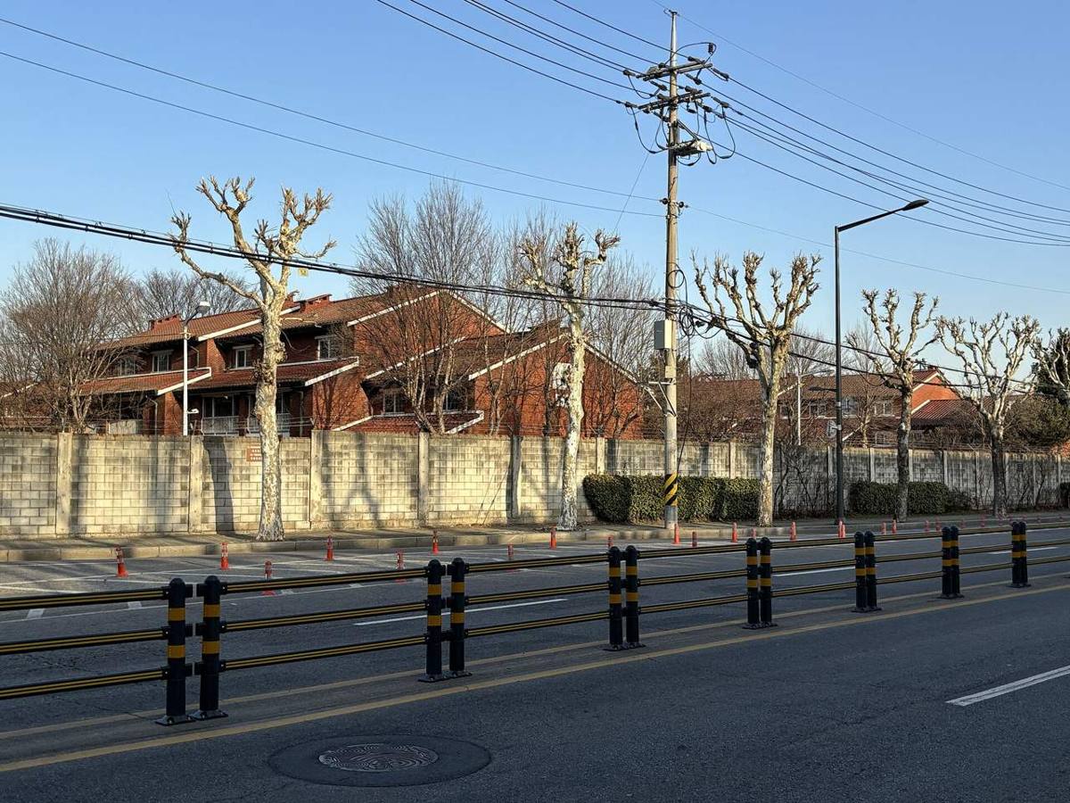 Two-storey red-brick American-style houses behind a concrete wall and plane trees in the former Loring Village of US Army Garrison Yongsan, now part of Yongsan Park in Seoul.