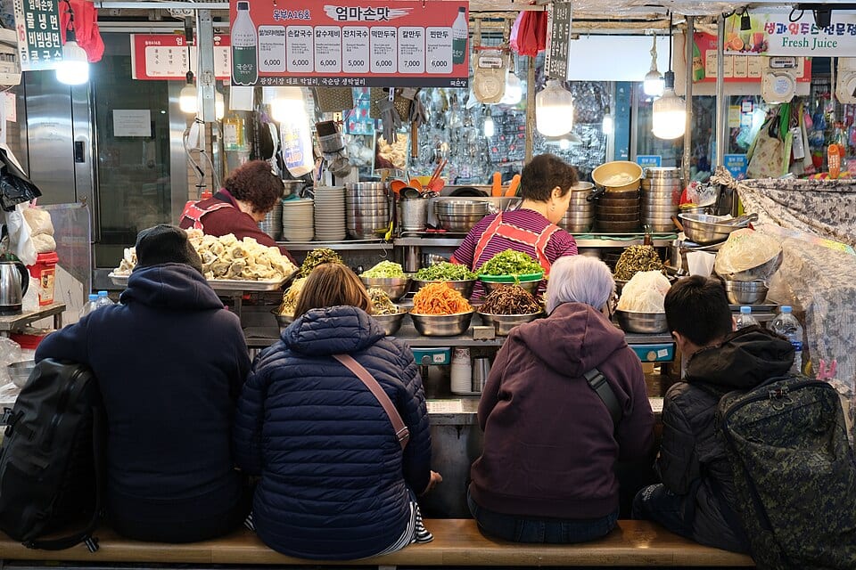 Customers seated at a Gwangjang Market food counter in Seoul