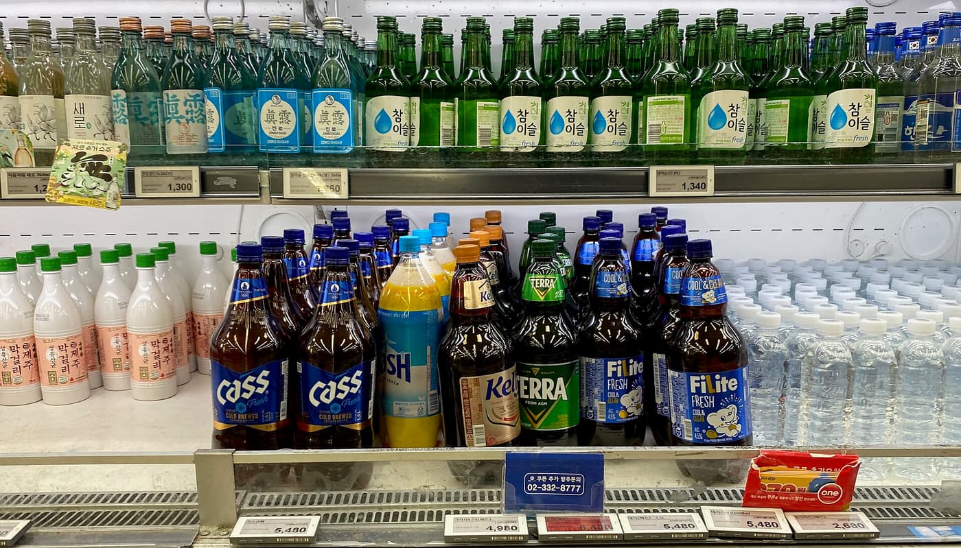Korean beer, soju and makgeolli bottles standing together.