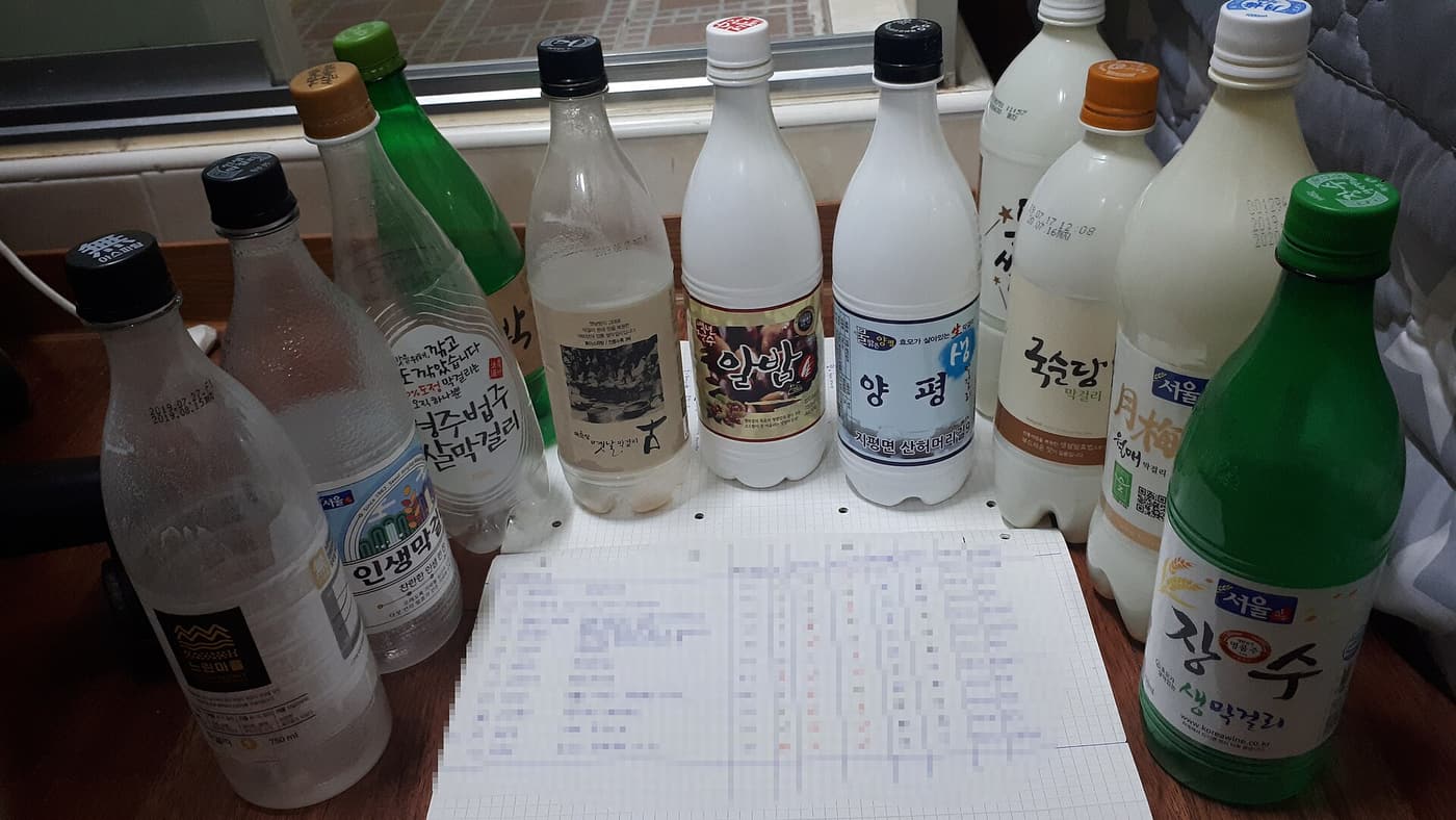 Several bottles of makgeolli in different brands lined up together.
