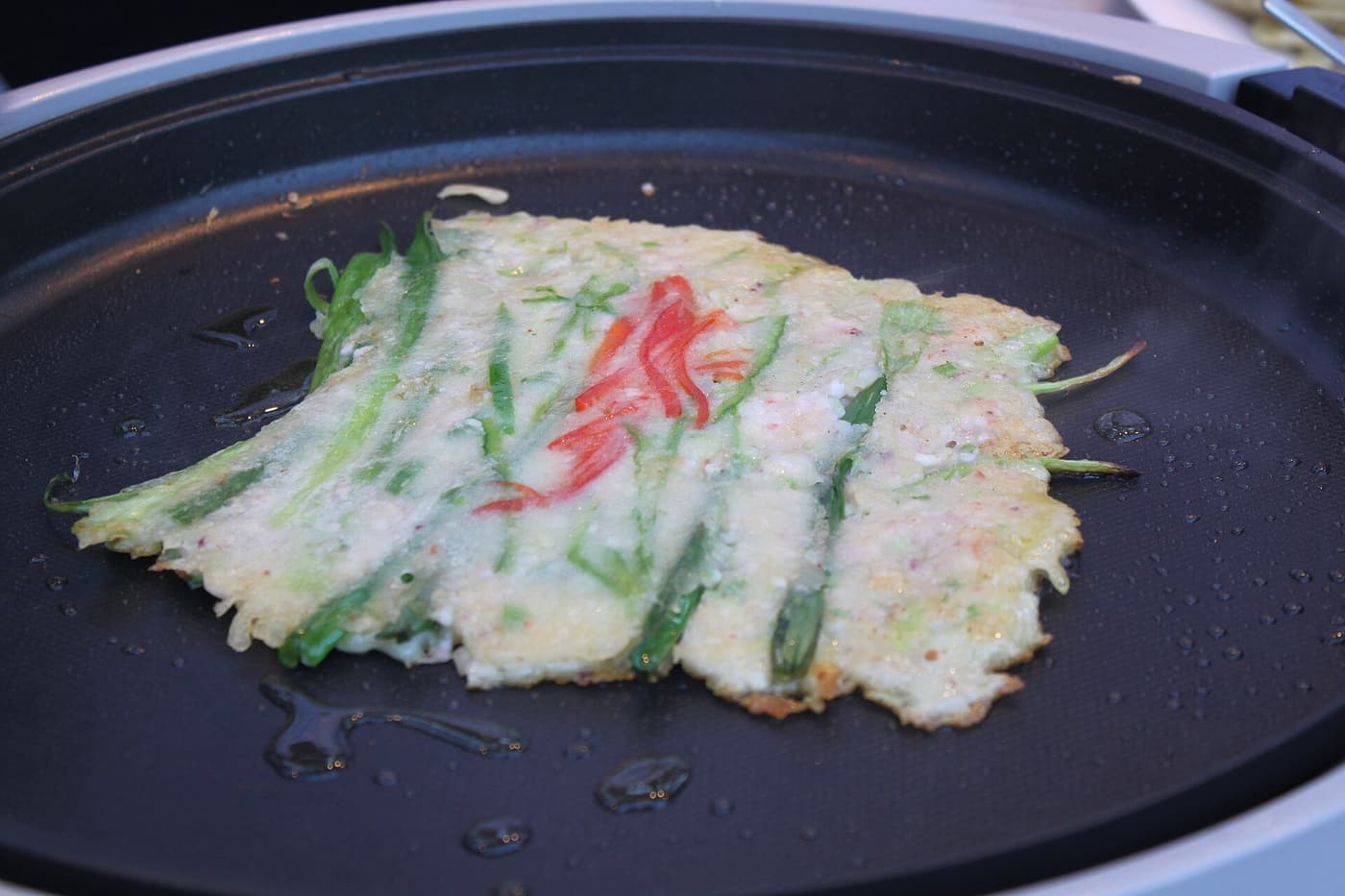 A scallion pancake frying in oil.