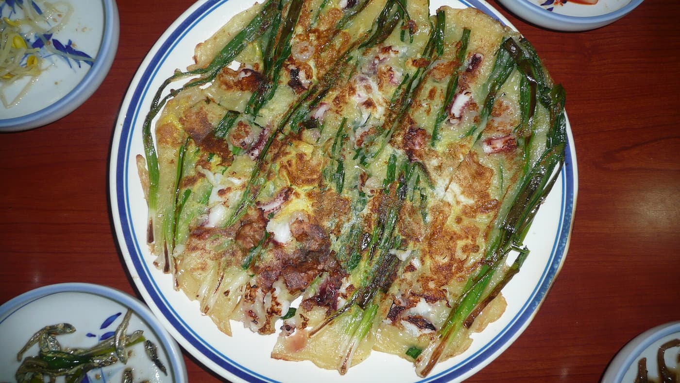 A finished pajeon cut into pieces and served on a plate.