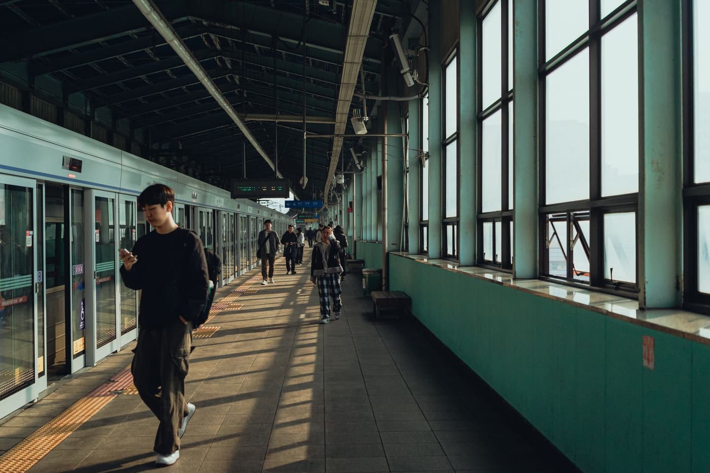 Commuters waiting on a Seoul metro platform, the concourse stretching away behind them.
