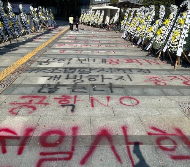Protest slogans and funeral wreaths along a Dongduk Women's University campus walkway.