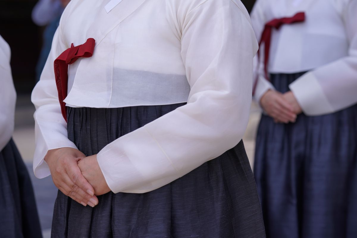 Women wearing colorful hanbok during a Korean outdoor ceremony