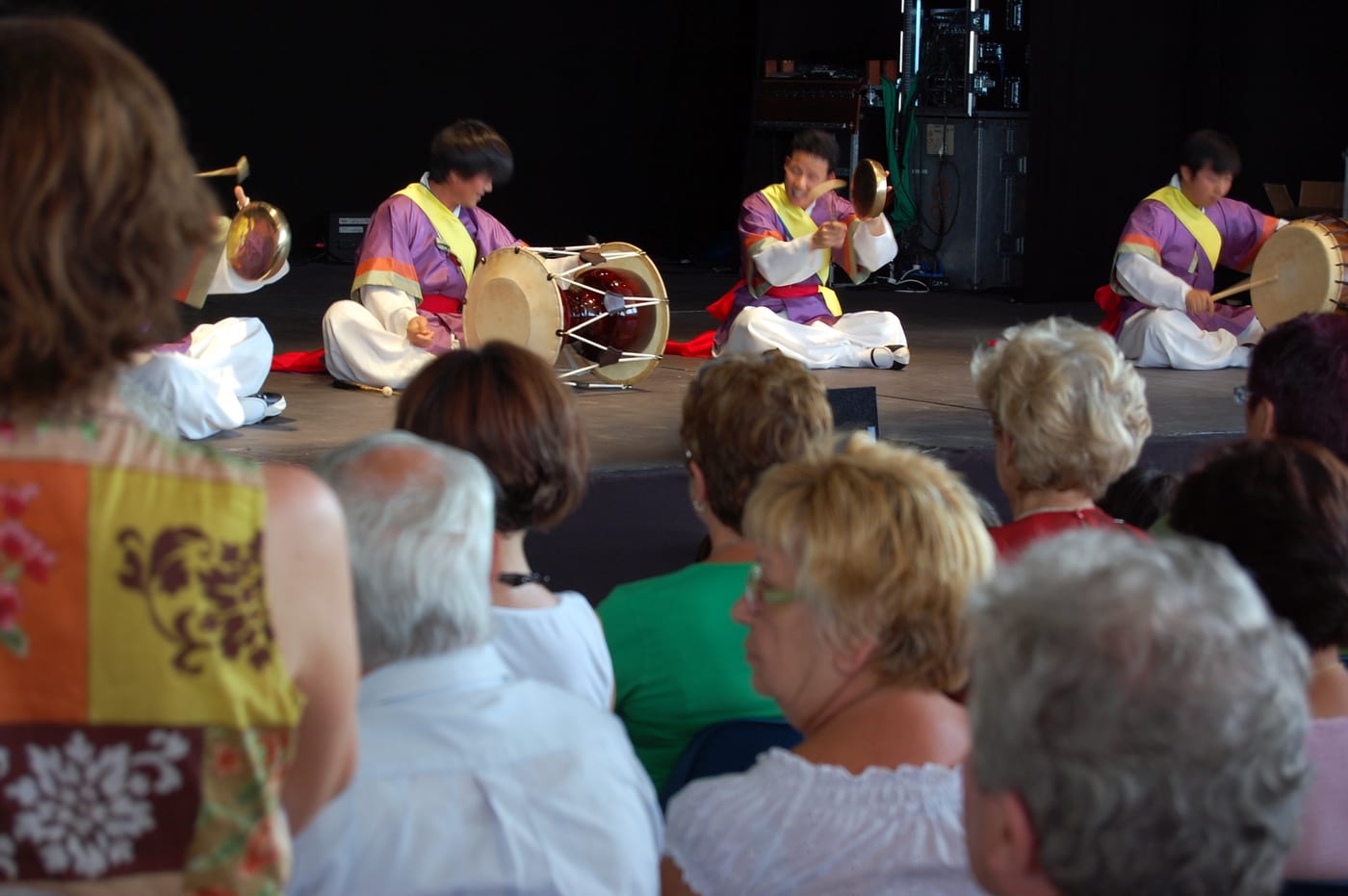 A seated samulnori quartet performing for an audience.