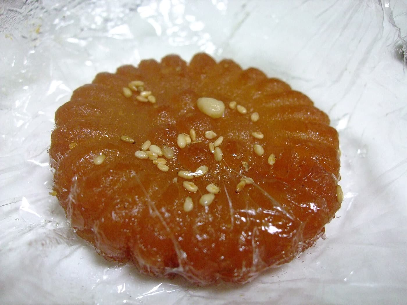Flower-shaped yakgwa, deep-fried honey cookies with a glossy syrup coating, arranged on a plate.