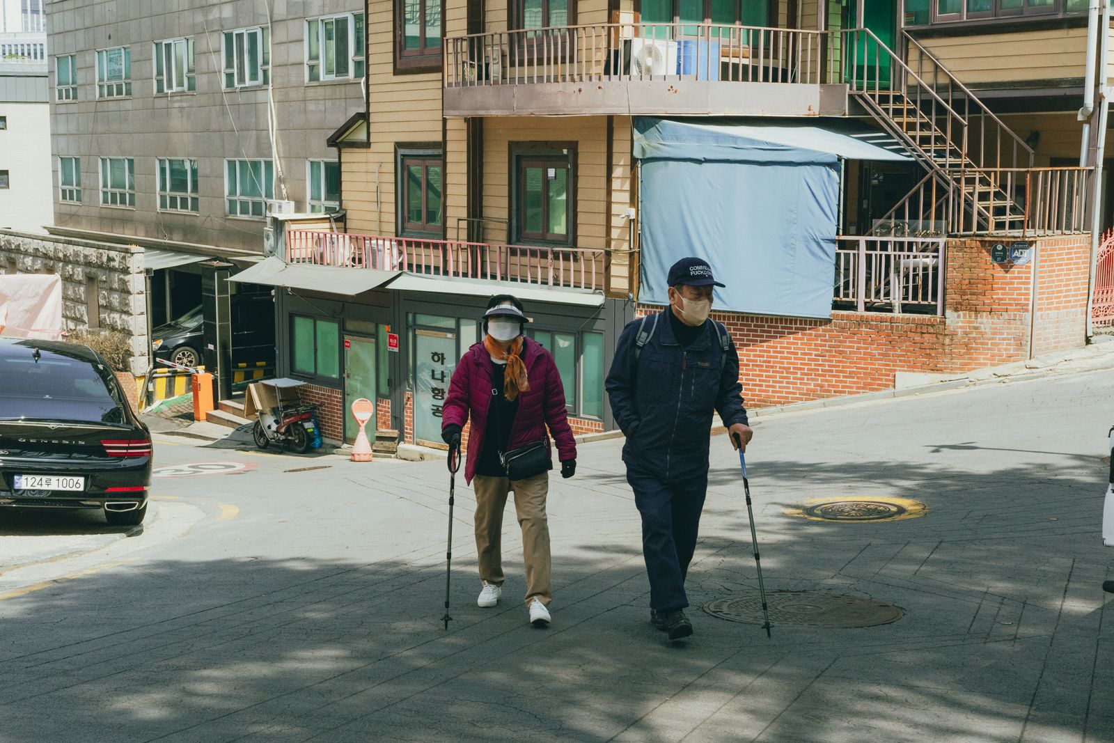 An older couple walking together on a residential hill in Seoul