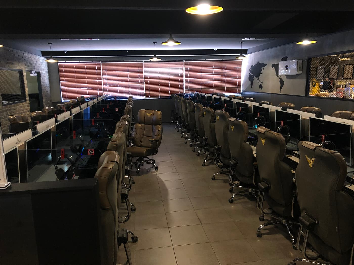 Desks and monitors in a PC bang, with keyboards, headsets and space beside each screen.