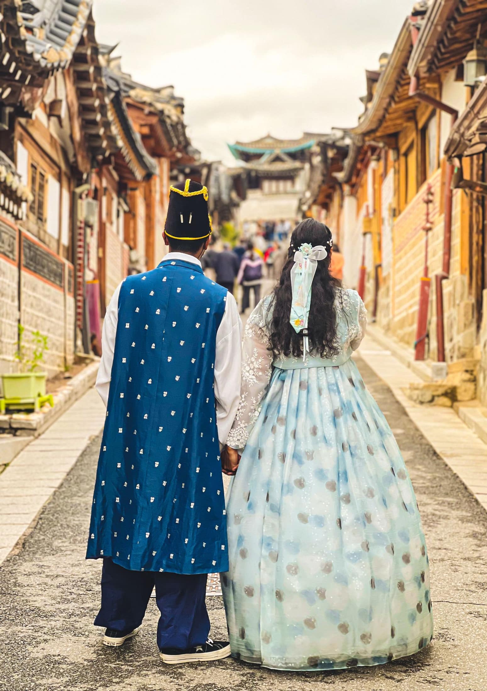 A couple wearing hanbok walks through Bukchon Hanok Village.