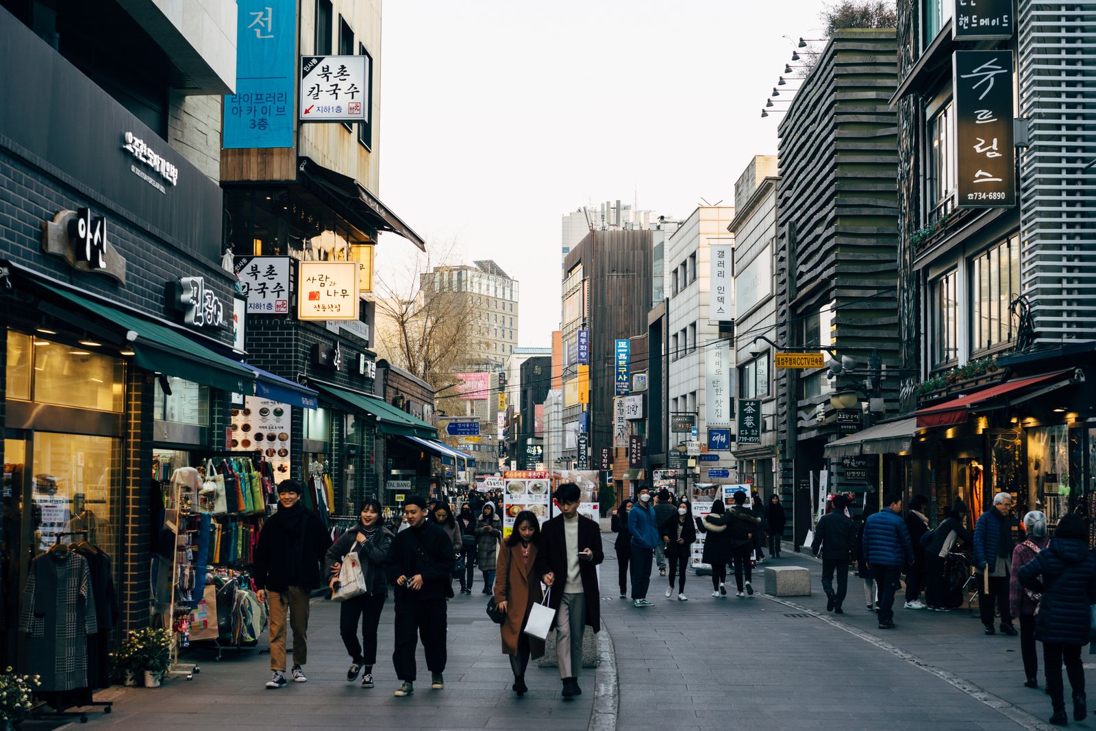 Pedestrians walking down Insadong-gil in Seoul past shops with Korean signage.
