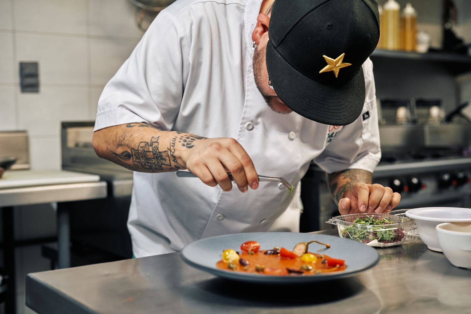 A chef carefully garnishing a plate in a professional kitchen