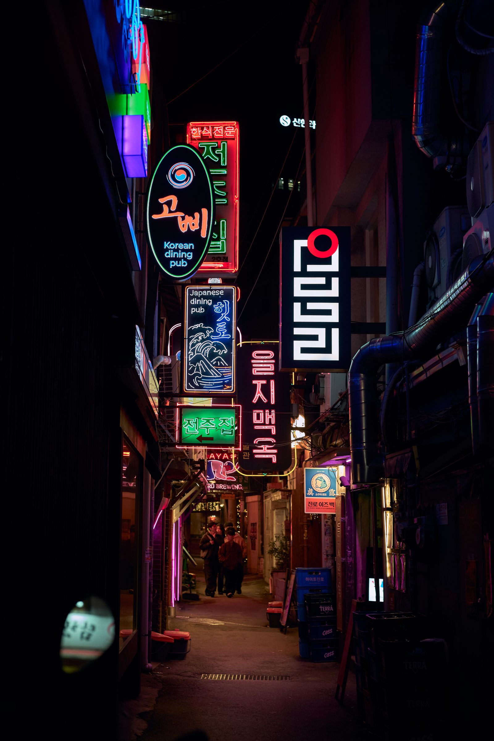 A night alley in Seoul lined with glowing Hangeul neon signs.