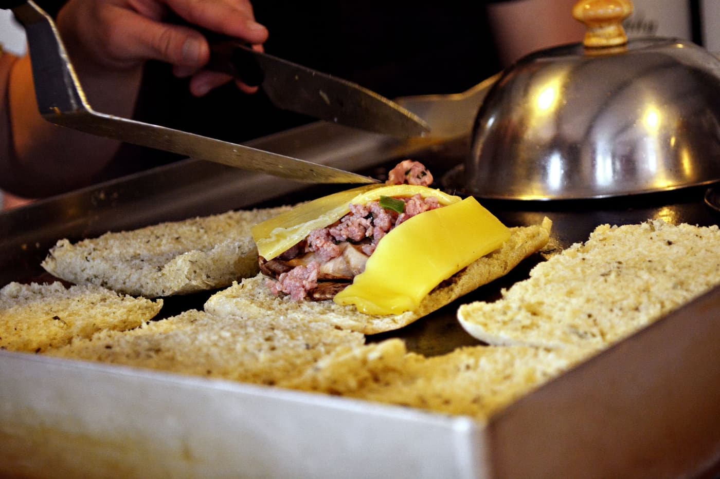 A sandwich cooking on a flat griddle, cheese melting between slices of bread.