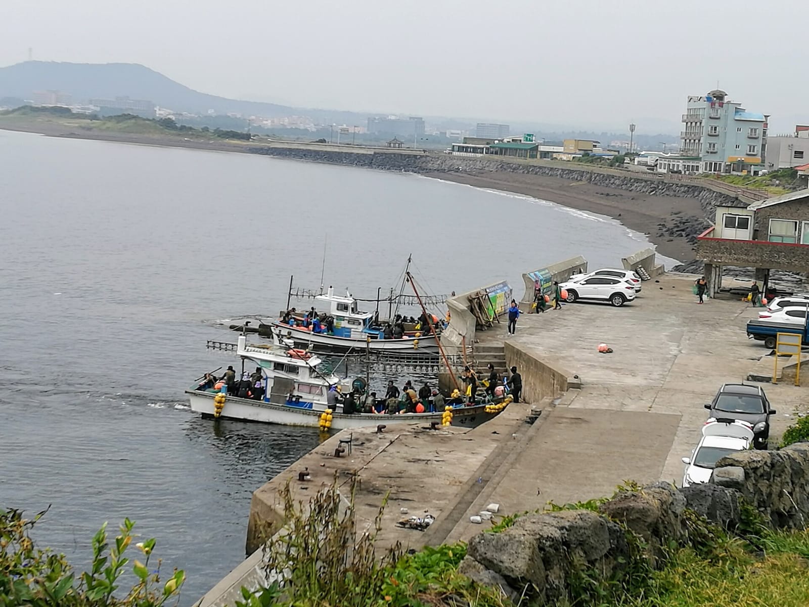 Haenyeo and small boats at a harbor below Seongsan Ilchulbong on Jeju Island.