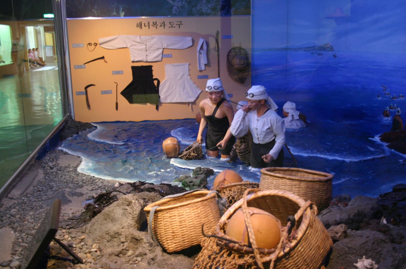 Museum exhibit displaying traditional haenyeo cotton diving clothes and tools.