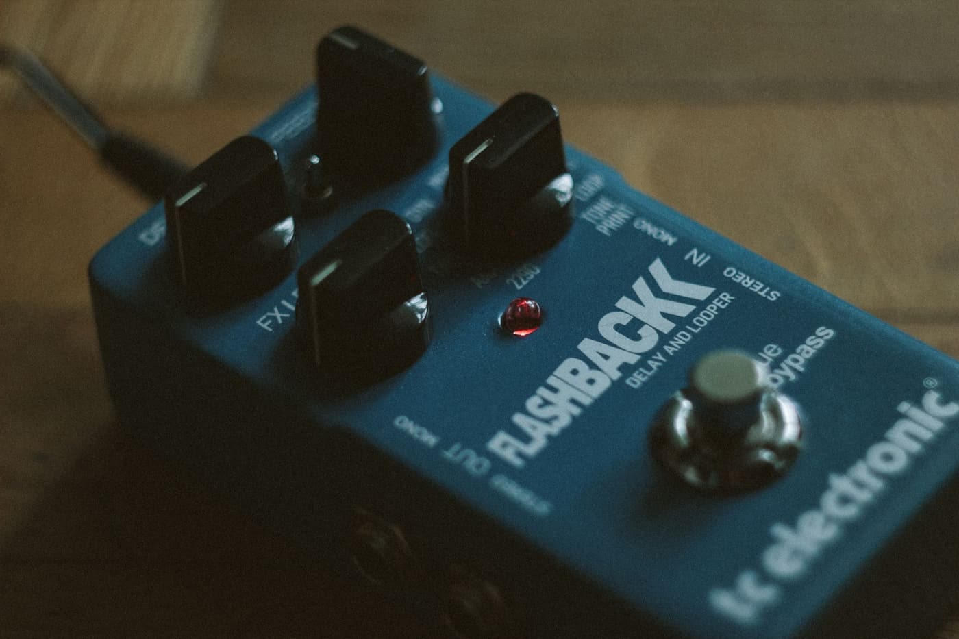 A looper pedal on a floor with cables running from it.