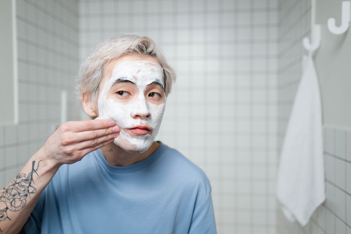 A man applying a facial mask in a bathroom