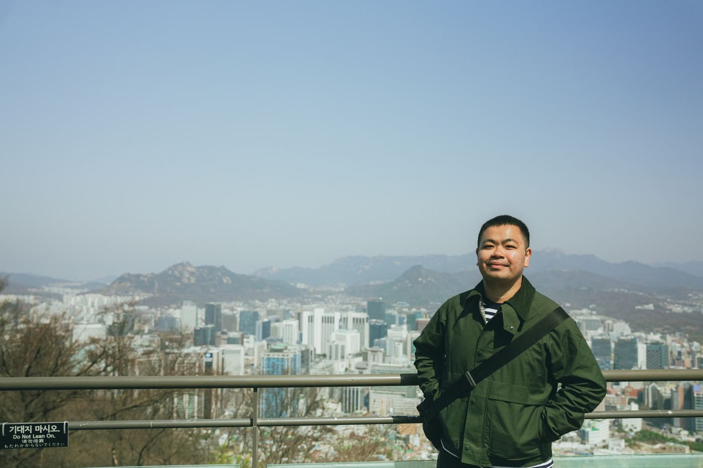 A person looking over the Seoul skyline from a mountain viewpoint