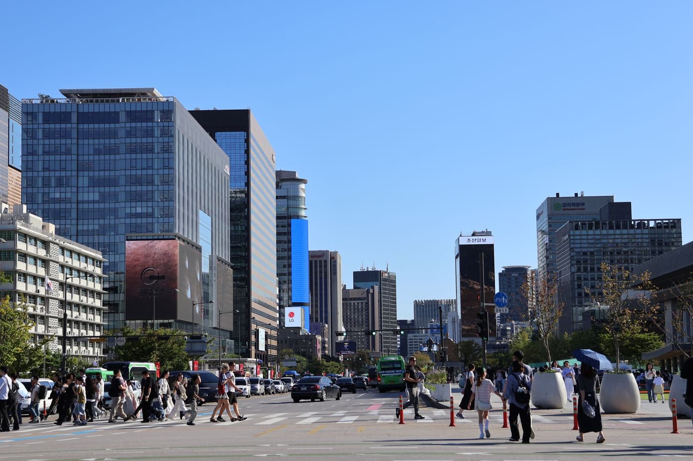 A modern Seoul street with tall buildings and people crossing