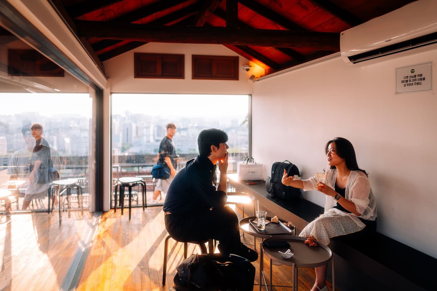 People chatting inside a Seoul cafe with city views nearby.