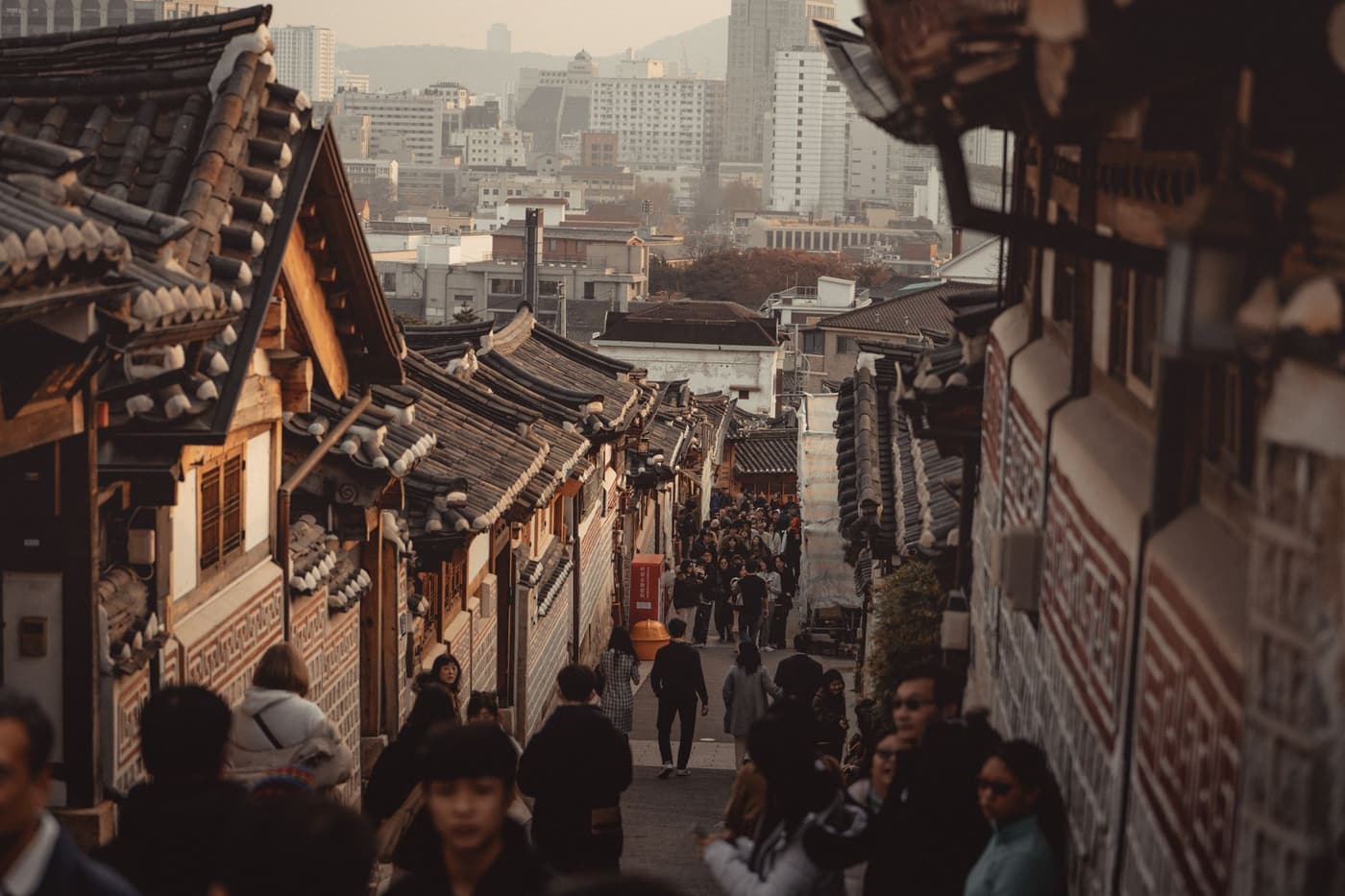 A bustling Bukchon Hanok Village street with traditional Korean architecture.