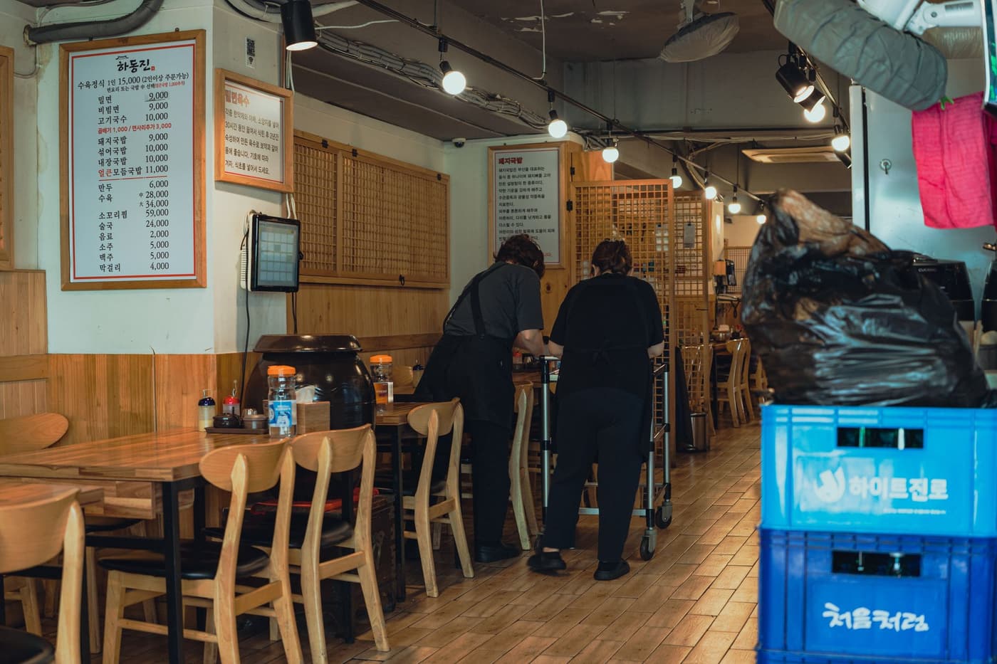 A warm interior of a traditional Korean restaurant in Seoul with staff preparing tables.