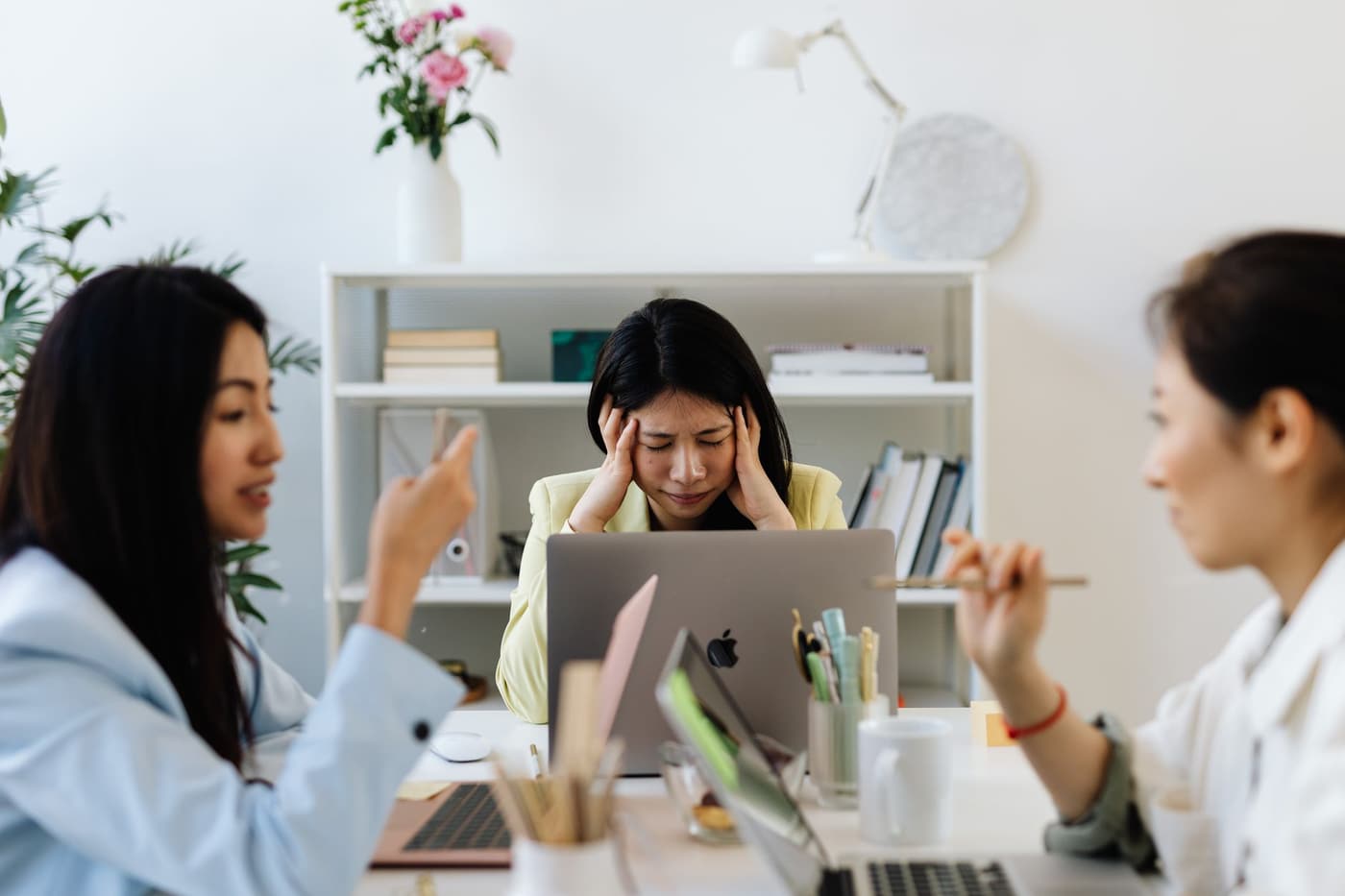 An Asian businesswoman looks stressed during an office discussion with colleagues.