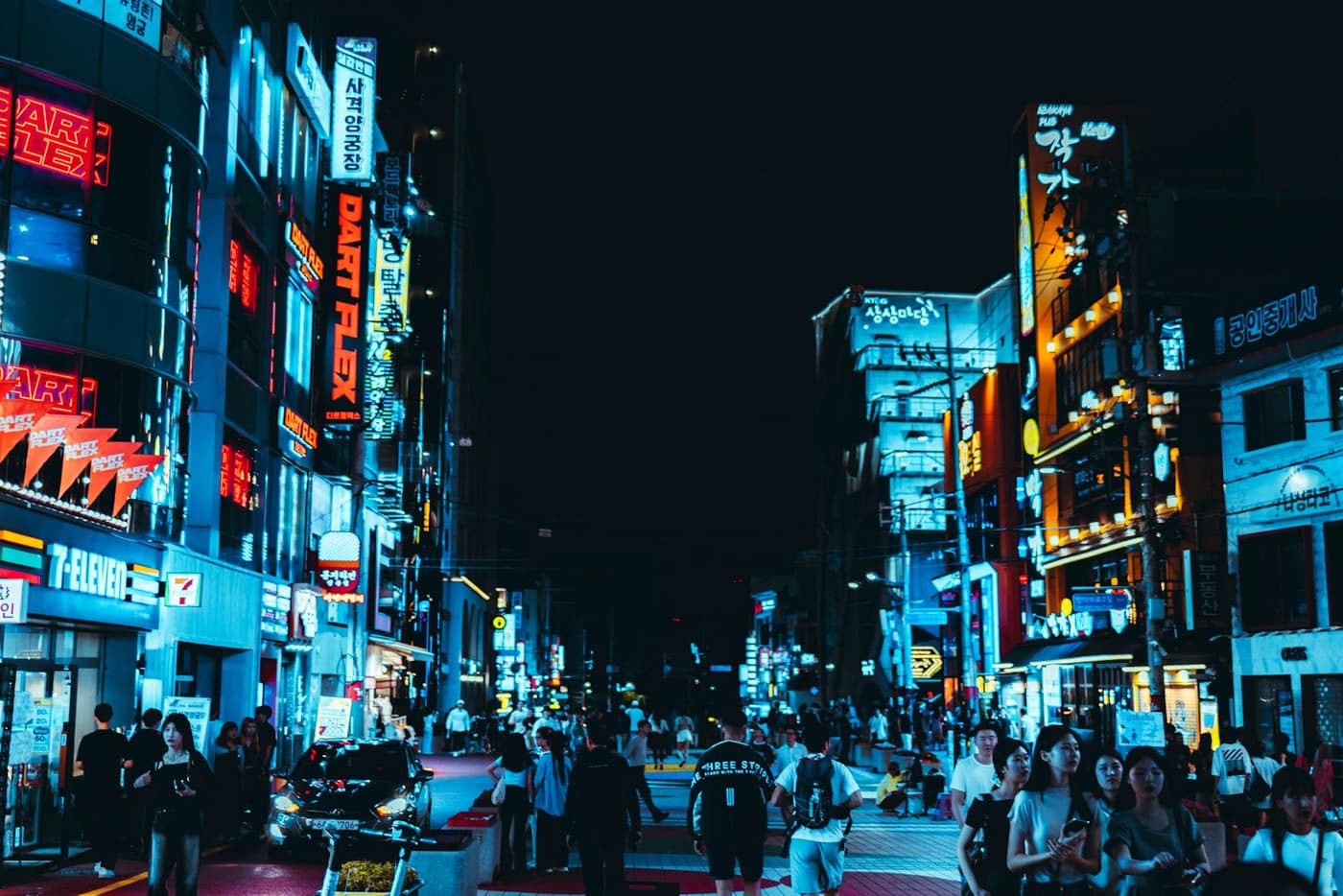 Hongdae Street in Seoul with summer-night crowds and sleeveless tops visible in the foreground.