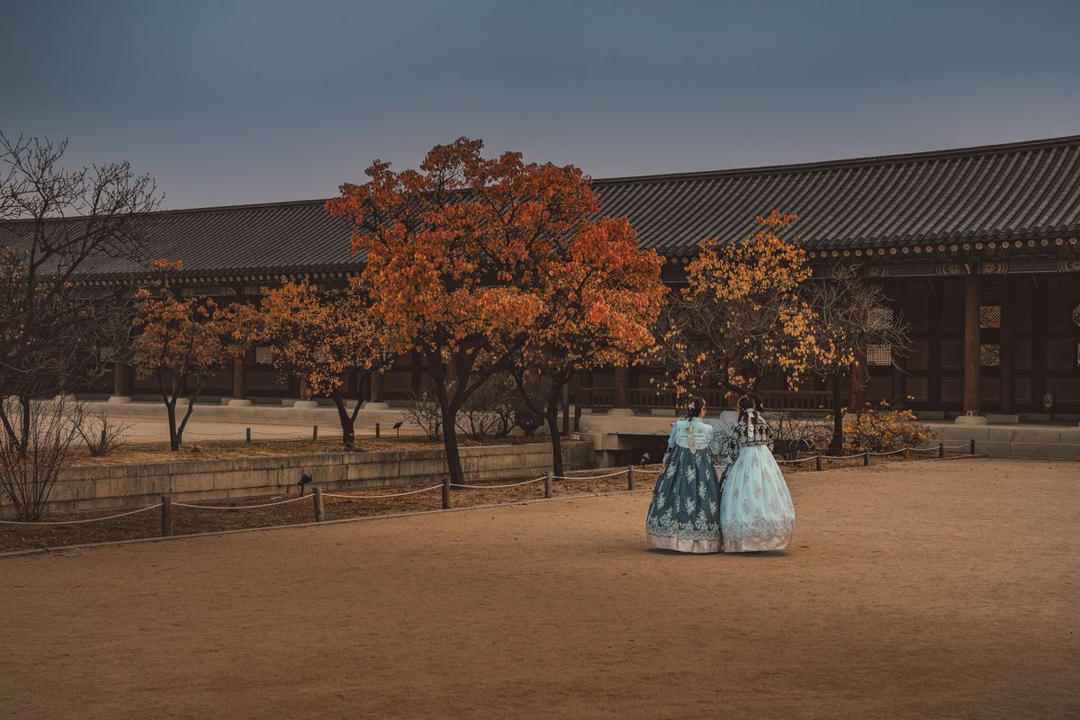Two women in hanbok walking through Gyeongbokgung Palace in autumn, fitting the cultural side of a Chuseok-season Seoul visit.