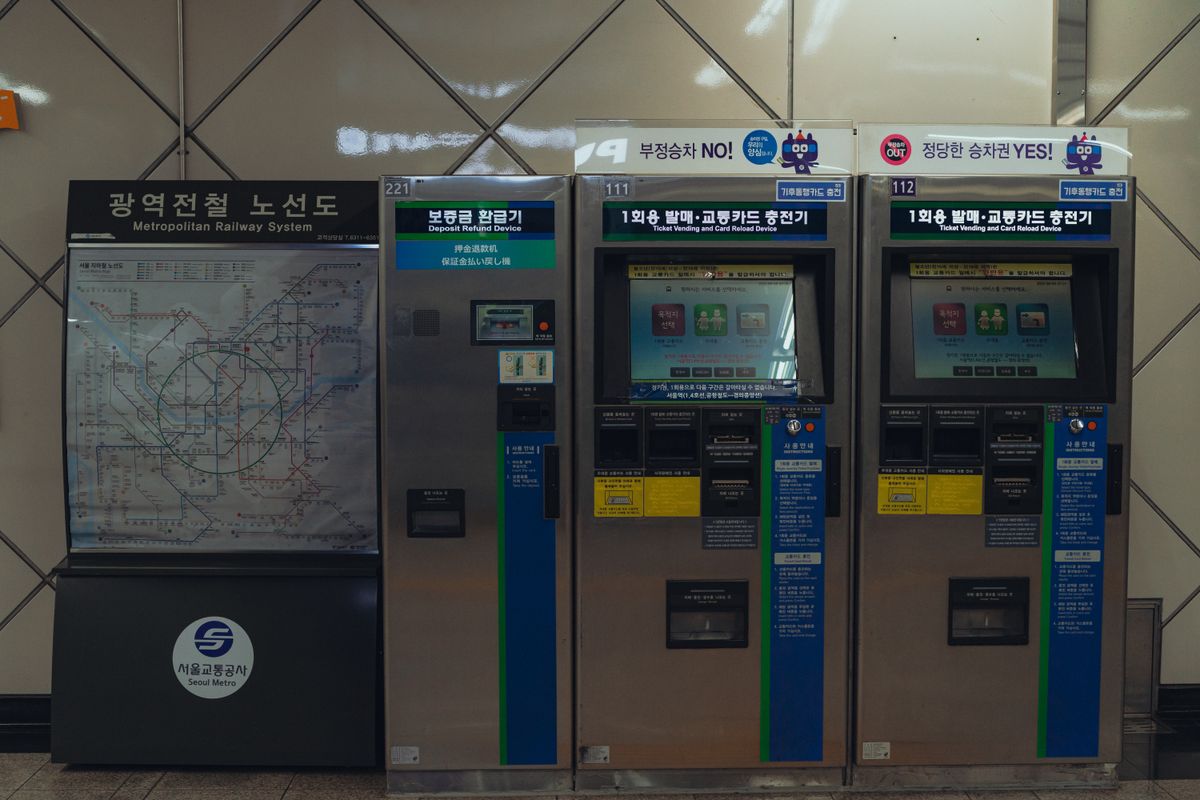 Seoul Metro ticket vending and card recharge machines beside a metropolitan railway map.