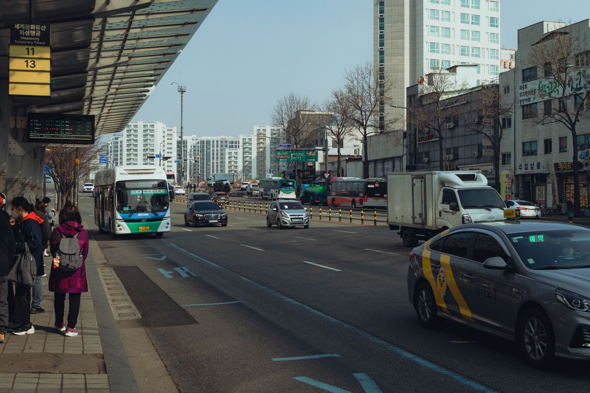 A busy Seoul street with buses, taxis, and pedestrians.
