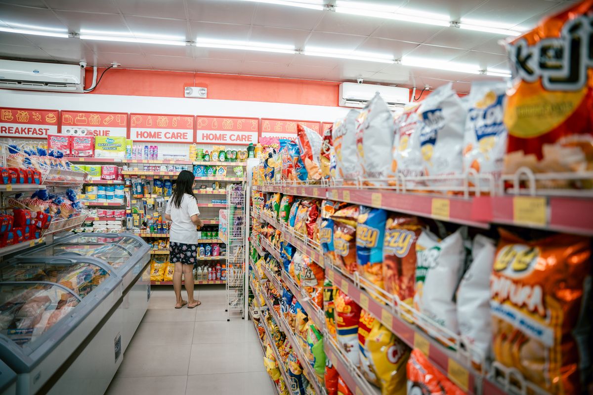 A shopper browsing snack shelves in a supermarket.