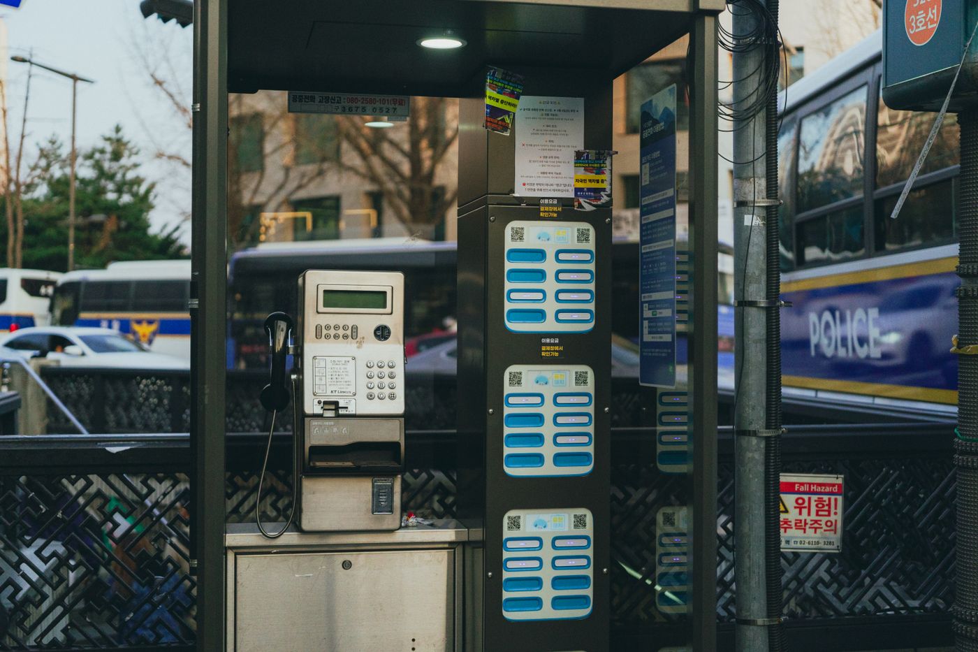 A Korean public phone booth near police vehicles, useful if your lost item is the phone itself.