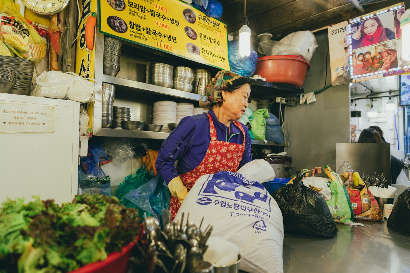 A Seoul market food stall with Korean menu text and ingredients, where travelers may need to ask about broth or meat base.