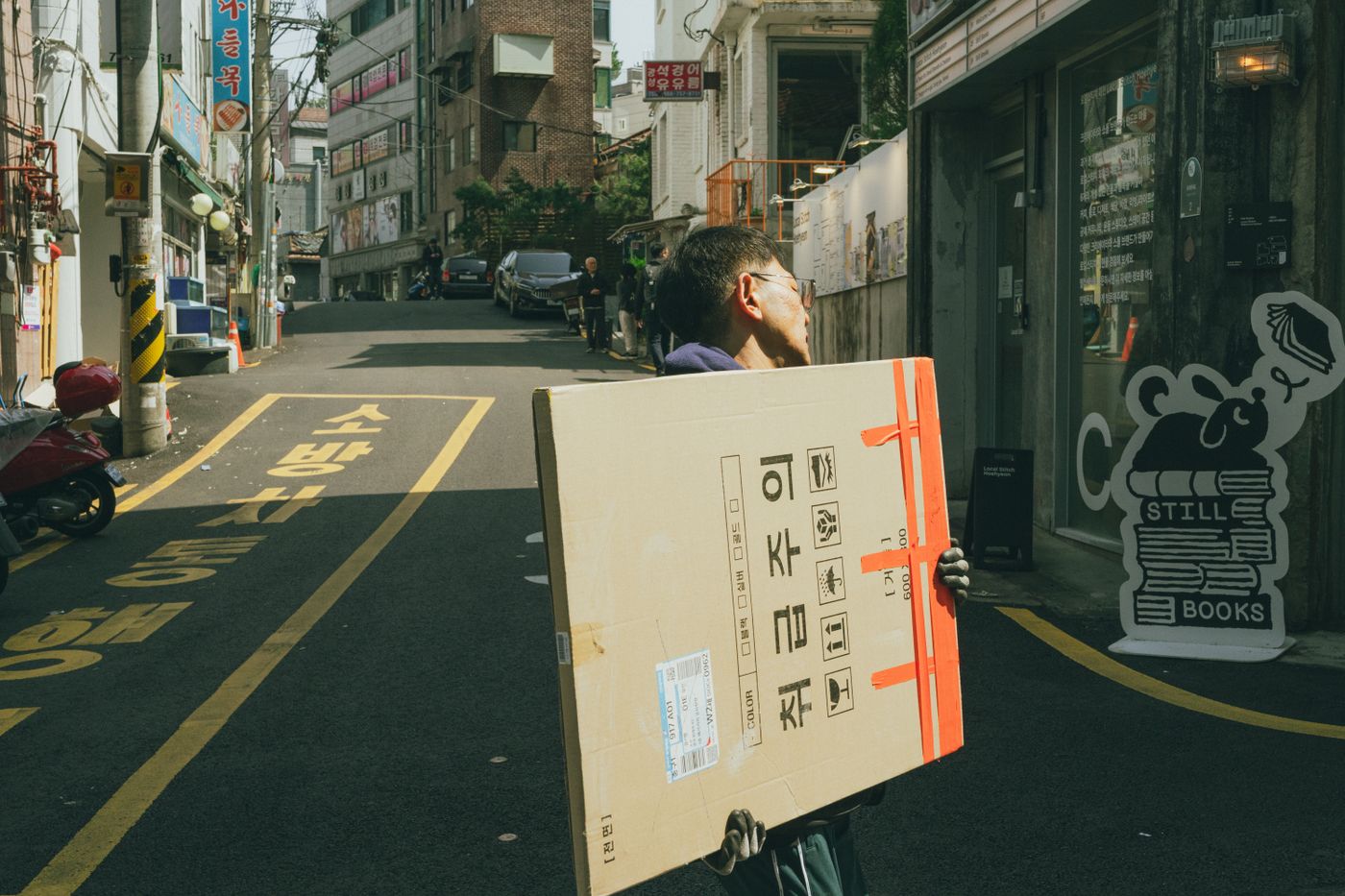 A Korean street scene with a person carrying a package, a reminder that the useful details are often on the back label or product page.