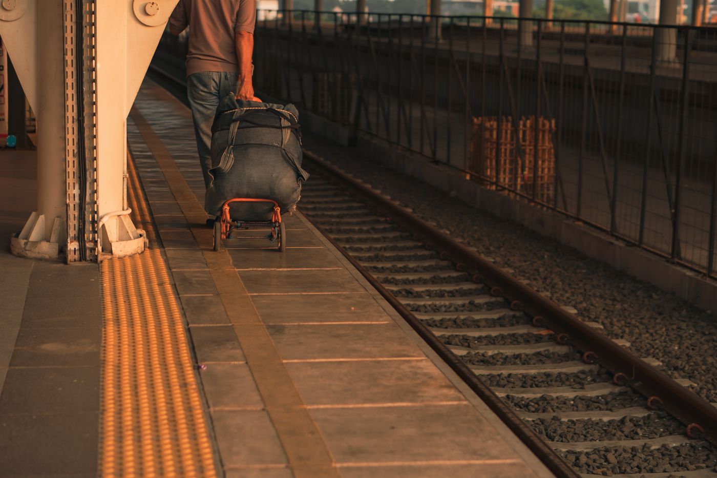 A traveler moving luggage on a station platform, a neutral visual for the physical reality of transit days.