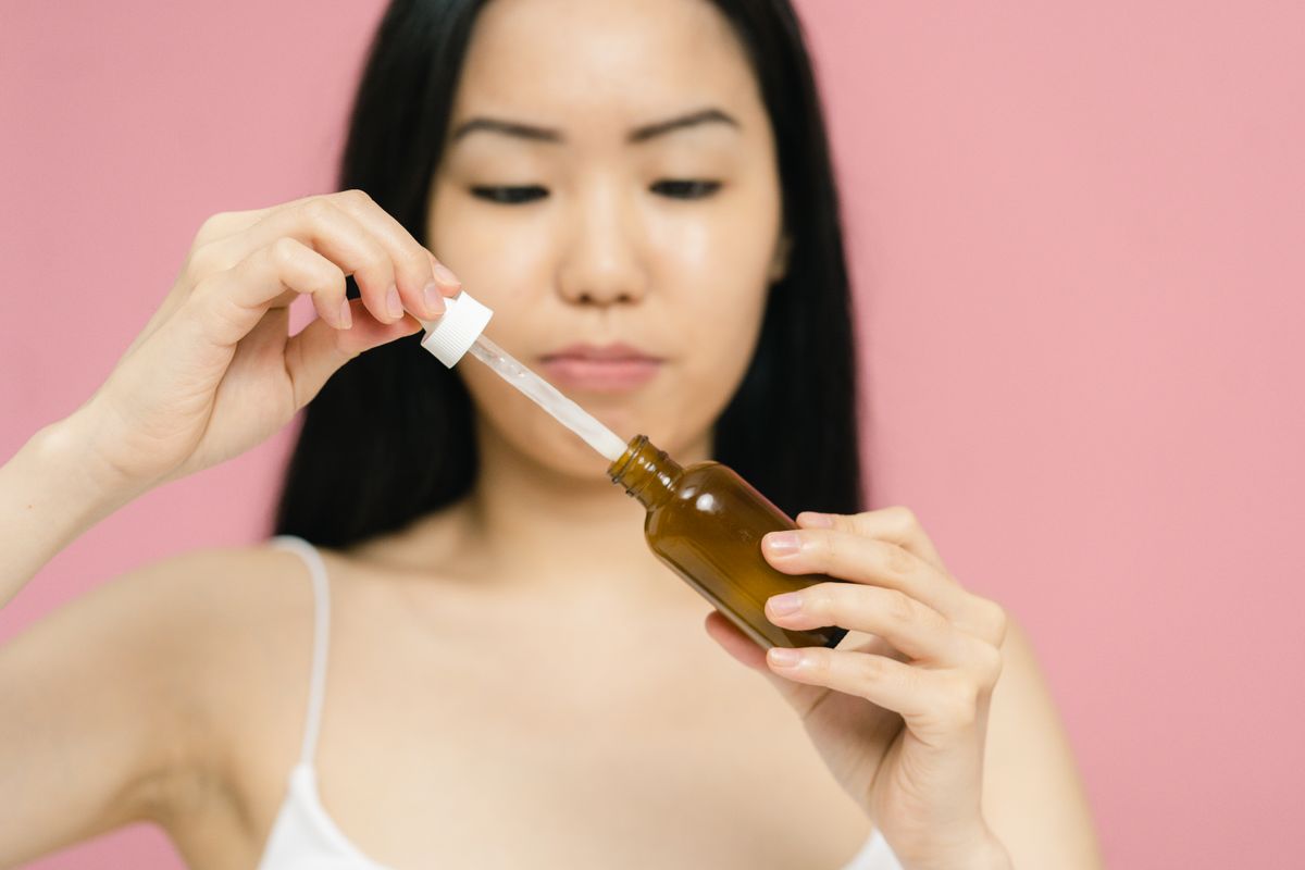 A woman applying serum from a dropper, showing how Korean skincare trends often become practical only when the texture fits a daily routine.