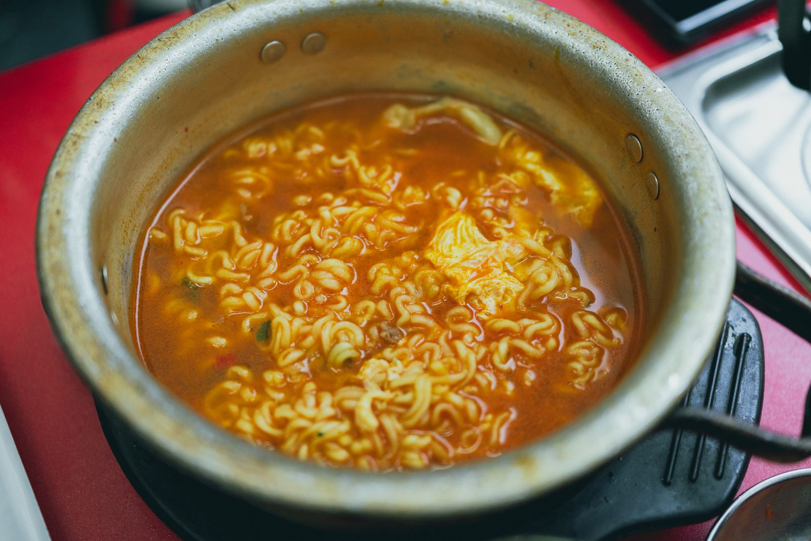 A small Korean ramen pot with spicy broth and noodles, representing the comfort side of Korean ramen trends.